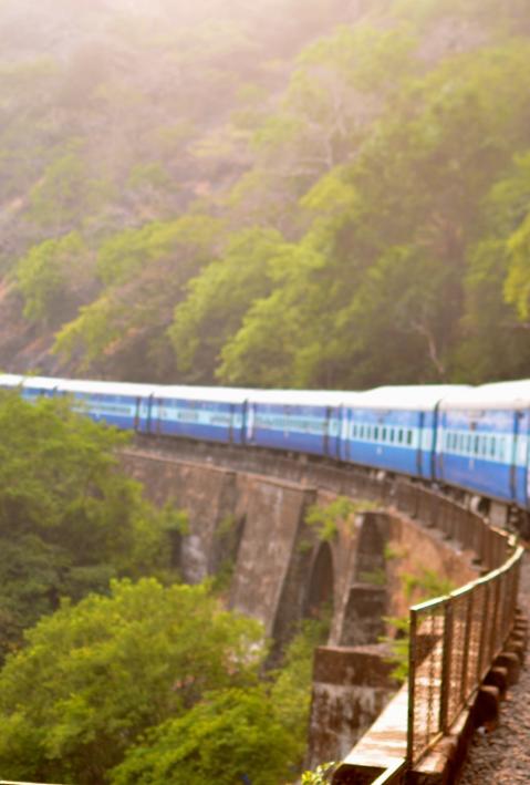 Eine Frau schaut aus einem Zugfenster. Der Zug fährt auf einer Brücke durch eine Berglandschaft.  