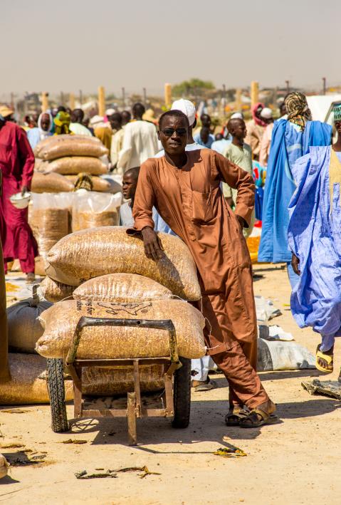 Eine Person auf einem Markt lehnt sich an Getreidesäcke an