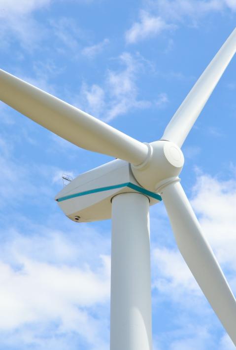 Close up of wind turbine against blue sky. 