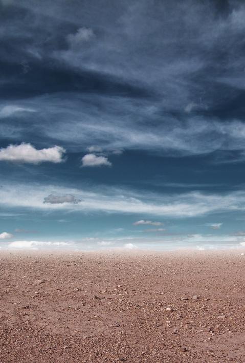 Gray clouds hang over barren desert. 