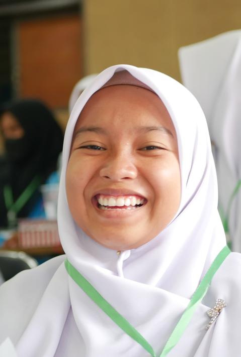 Ein indonesisches Schulmädchen lächelt in die Kamera. 