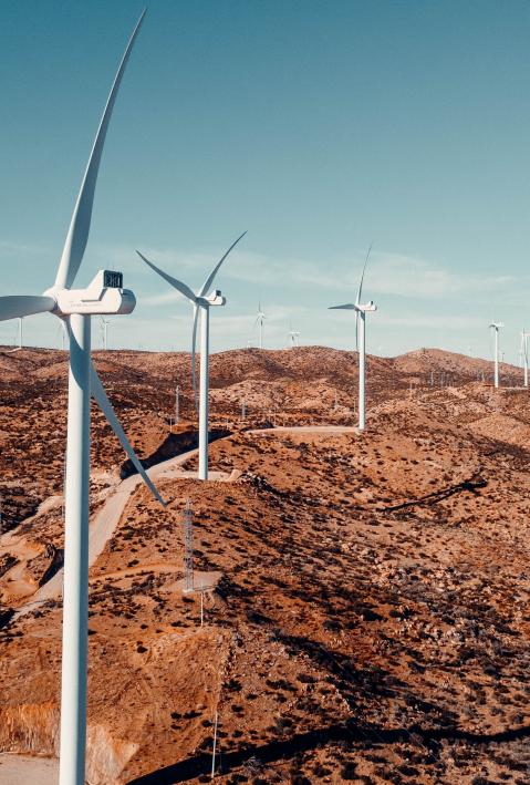 Wind turbines on a barren hilltop. 