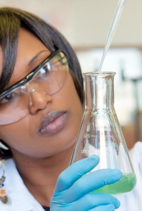 African female researcher with glass equipment in the lab - soft focus on glass and hands.